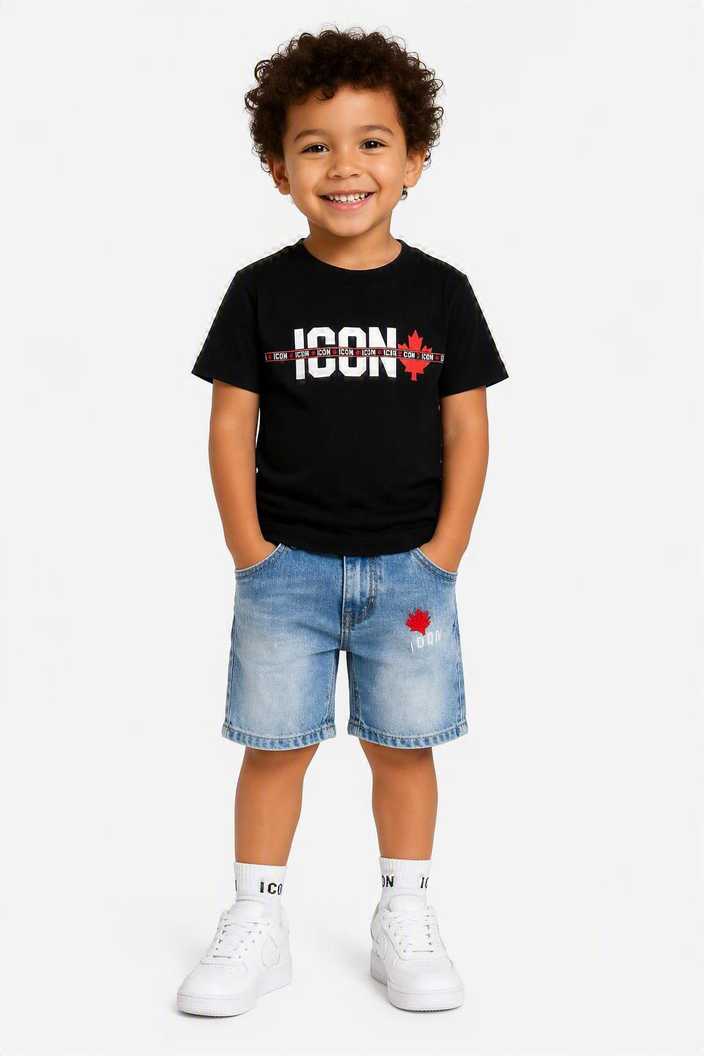 Kindmodel draagt een zwart ICON T-shirt met witte opdruk en rode esdoornblad-details, gecombineerd met een lichtblauwe denim short met rode accenten. Trendy en comfortabele zomeroutfit voor kinderen, geschikt voor dagelijks gebruik en casual gelegenheden. Beschikbaar in de maten 4, 6, 8, 10, 12 en 14.