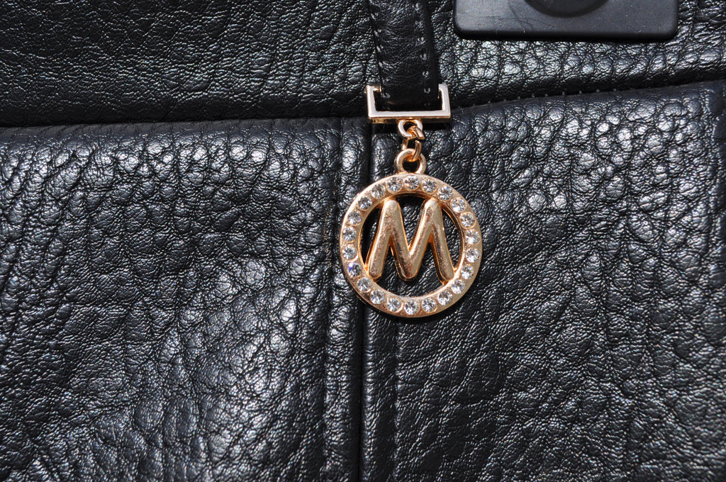 "Gouden M-badge rhinestones close-up zwarte imitatieleren broekrok"

