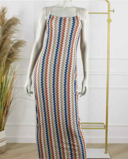 Rimini maxi jurk beige met blauw en roestkleurig zigzagpatroon, aansluitende lange damesjurk met schouderbandjes gepresenteerd op een mannequin in een lichte studioomgeving, onderdeel van de damescollectie van DeNa Kids Boutique.