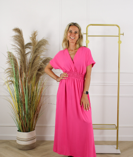 Modena maxi jurk in felroze met V-hals, korte mouwen en elastische tailleband, gedragen in een lichte studioomgeving. Elegante lange damesjurk uit de damescollectie van DeNa Kids Boutique.