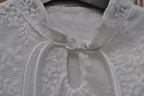 Witte kanten blouse meisjes hals detail parelknoop en strikkoordjes close-up
