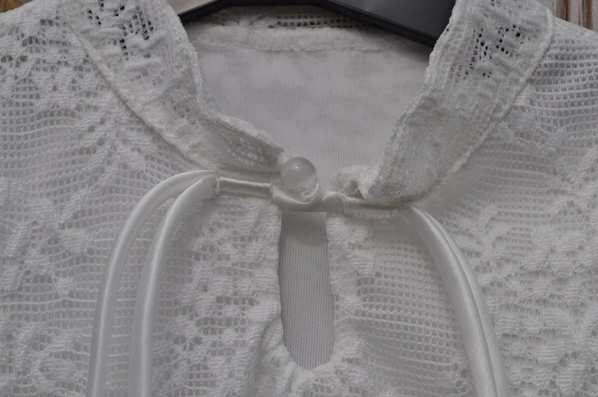 Witte kanten blouse meisjes hals detail parelknoop en strikkoordjes close-up