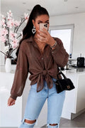 Bruine dames blouse met borduurwerk, lange mouwen en knoopsluiting, gestyled met een lichtblauwe jeans en zwarte handtas.