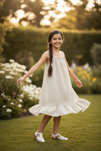 Meisjes beige linnen jurk met spaghettibandjes en ruche zoom - model 10 jaar - tuin achtergrond | DeNa Fashion