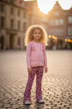 Meisjes flared broek roze geometrische print met roze ribstof top lifestyle blond krullend meisje 6 jaar stadsplein