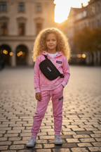 Roze ICON trainingspak lifestyle meisje 6 jaar blond krullend haar stadsplein met heuptas
