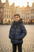 Jongen in donkerblauwe ICON gewatteerde winterjas op Europees kasseienplein
