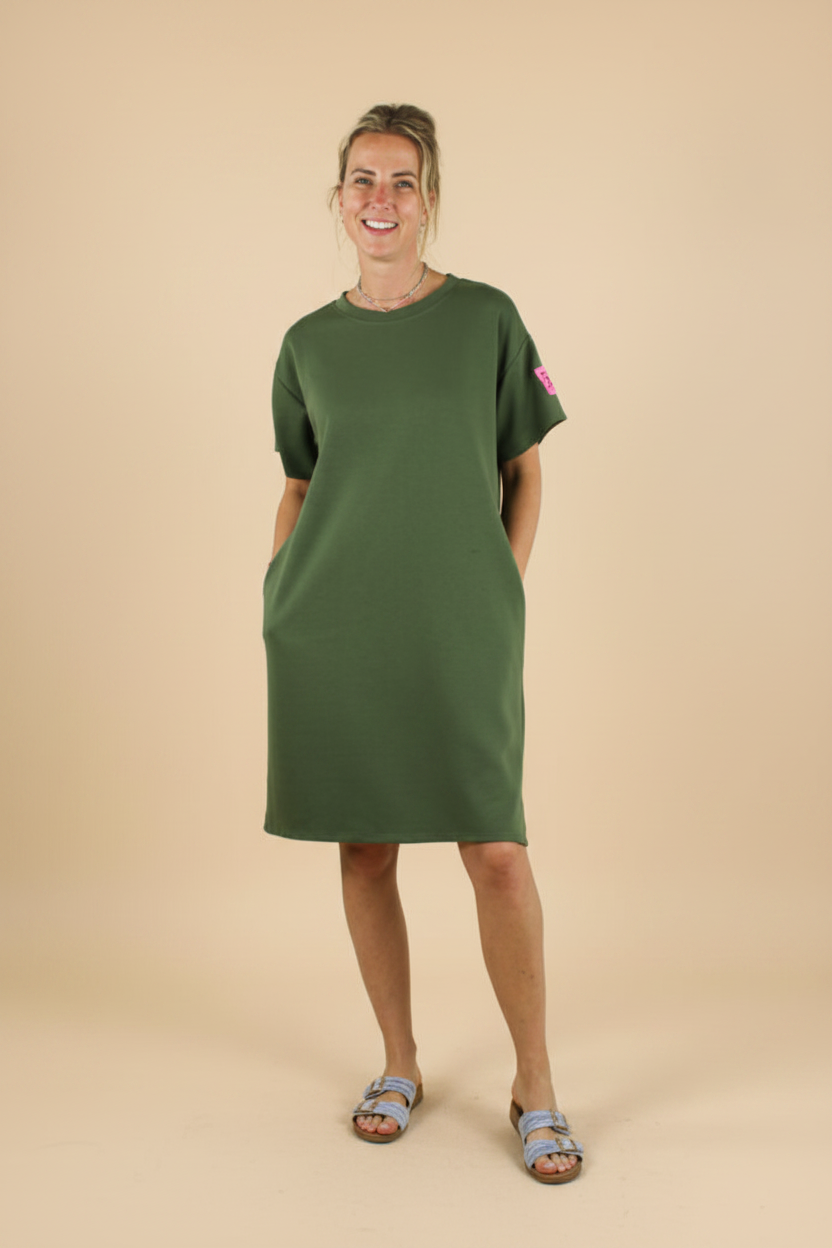 Dames army green midi jurk met korte mouwen, zijzakken en roze label patch — casual stoere jurk voor dames op lichtbeige studio achtergrond, Life Label maxi jurk army green