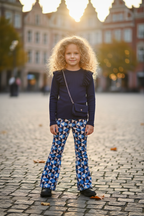 Meisjes flared broek geometrische print blauw met navy top lifestyle blond krullend meisje 6 jaar stadsplein