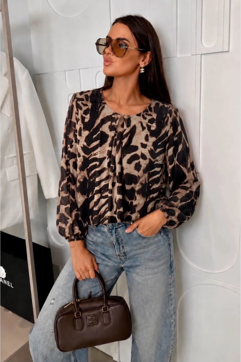 Dames panterprint top met lange mouwen en strikdetail bij de hals gecombineerd met een lichtblauwe jeans.