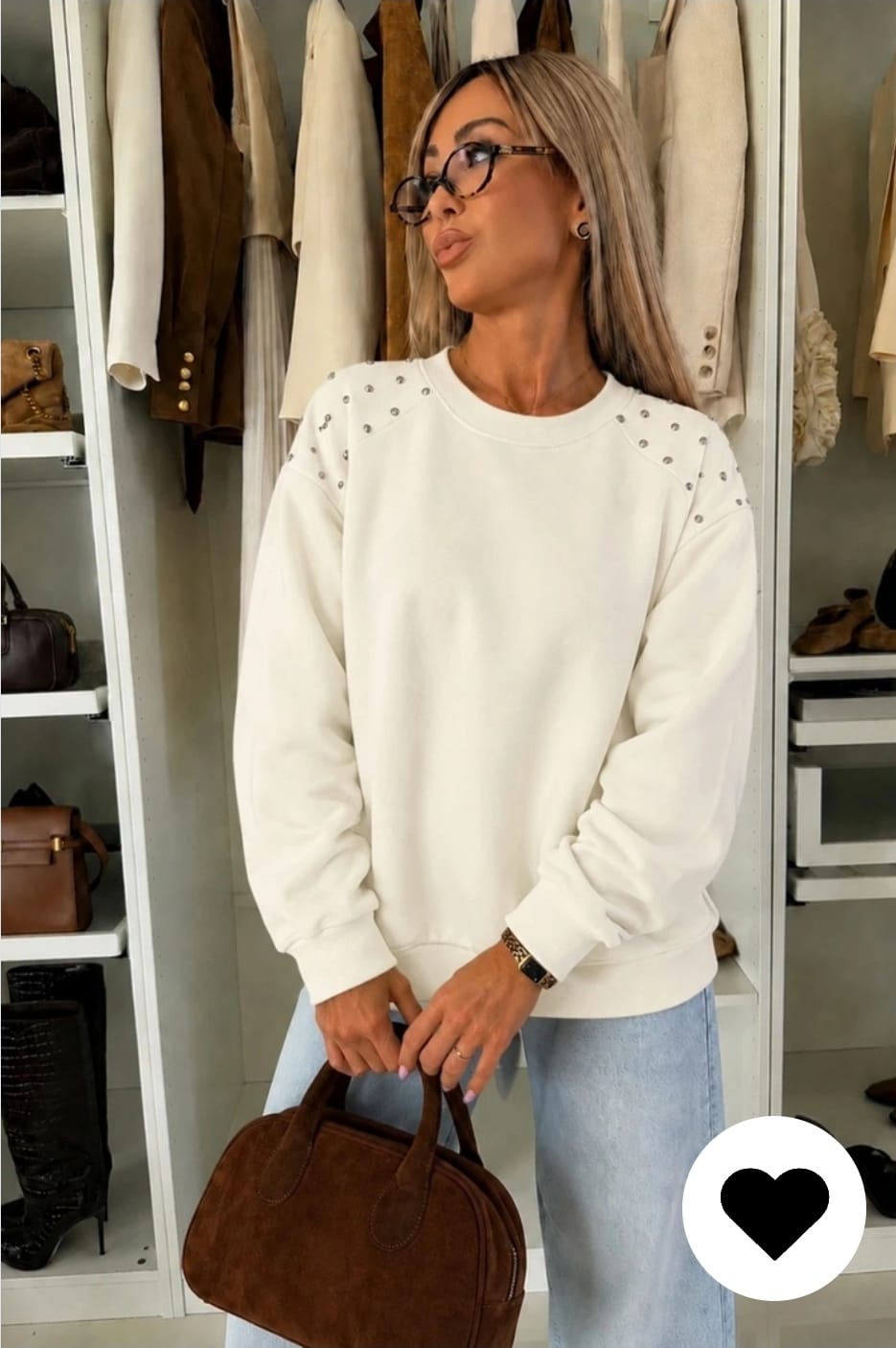 Witte dames sweater met parel details op de schouders, ronde hals en lange mouwen gecombineerd met een lichtblauwe jeans.